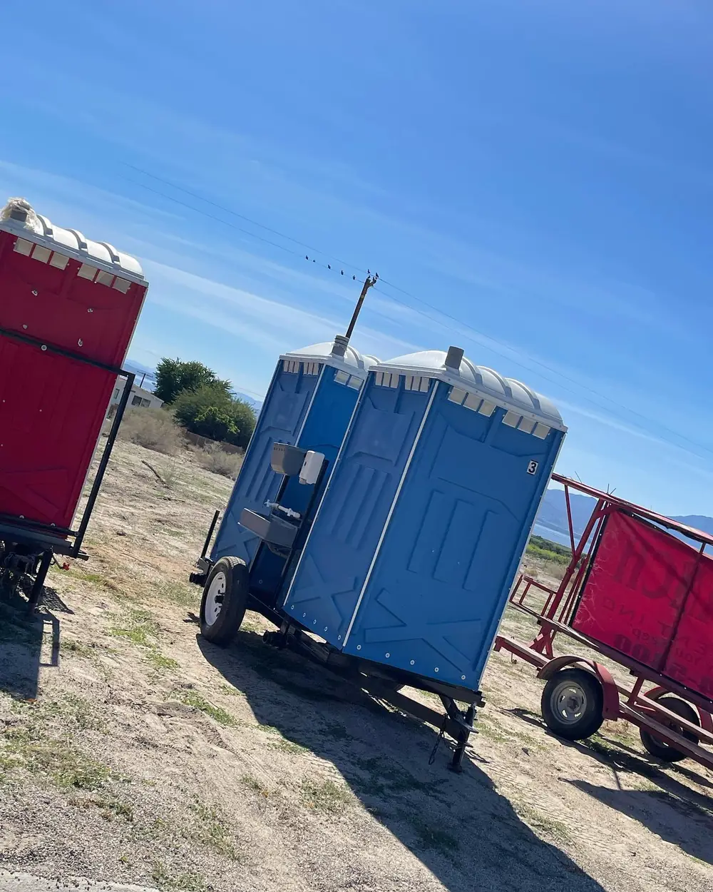 Gray porta potties lined up beside a residential driveway